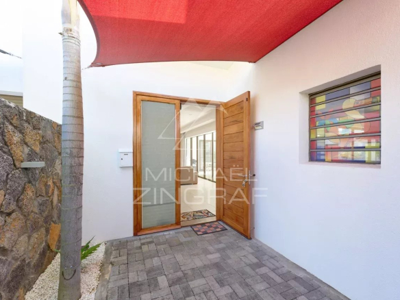 Entrée d'une villa contemporaine à Grand Baie avec un auvent rouge et un chemin en pavés.