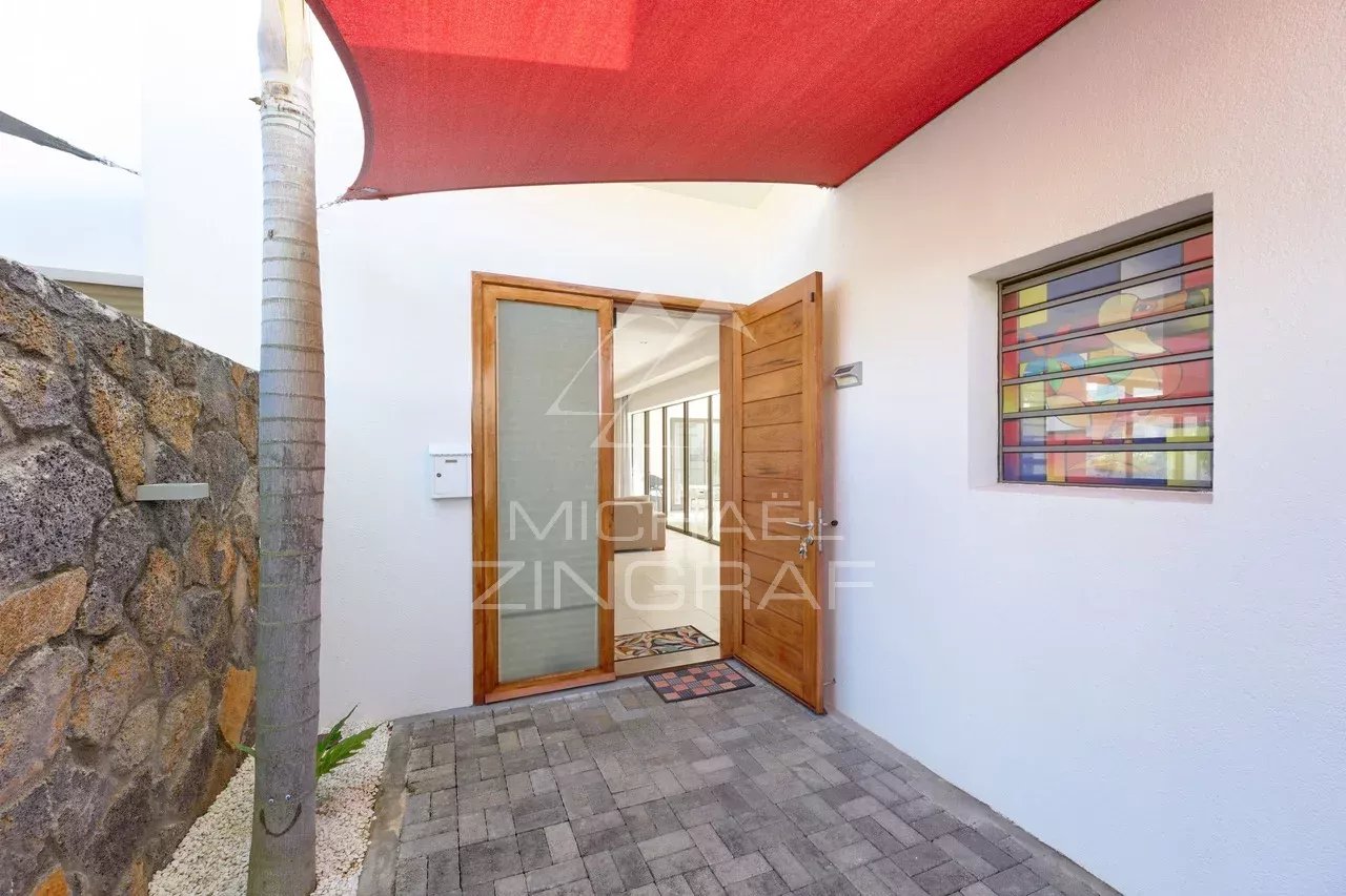 Entrée d'une villa contemporaine à Grand Baie avec un auvent rouge et un chemin en pavés.