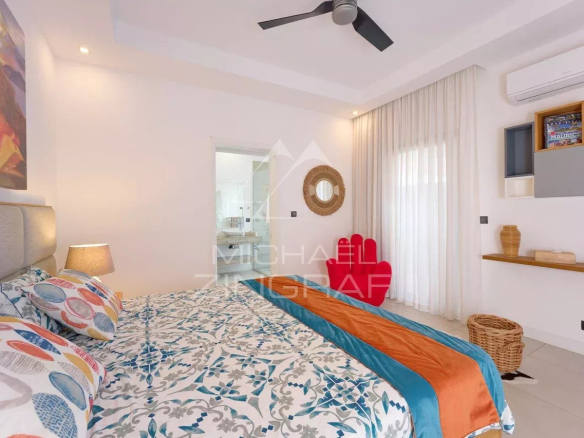 Chambre d'une villa contemporaine avec lit, décor coloré et accès à une salle de bain.