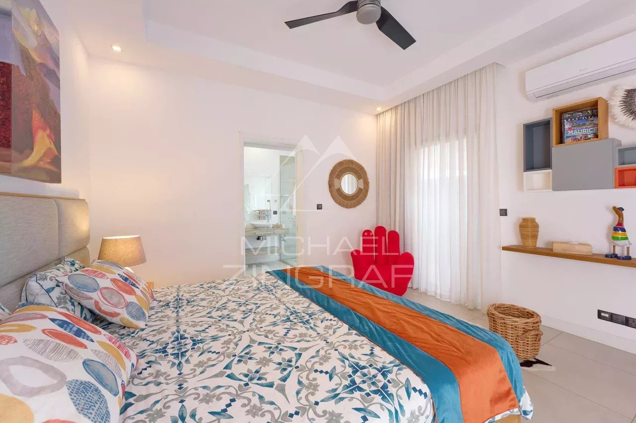 Chambre d'une villa contemporaine avec lit, décor coloré et accès à une salle de bain.
