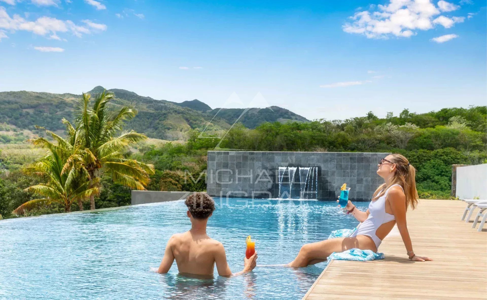 Détente au bord de la piscine Deux personnes se détendent au bord d'une piscine à débordement avec vue sur des montagnes verdoyantes.