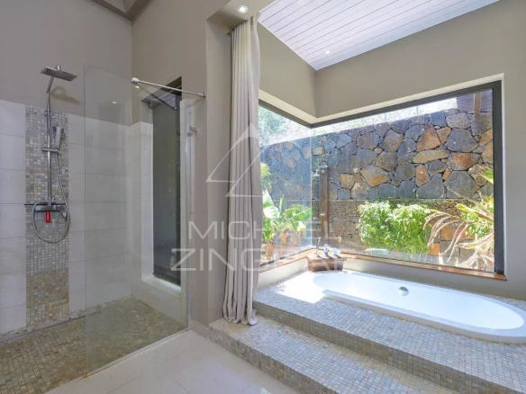 Salle de bain moderne avec douche et baignoire, vue sur un jardin.
