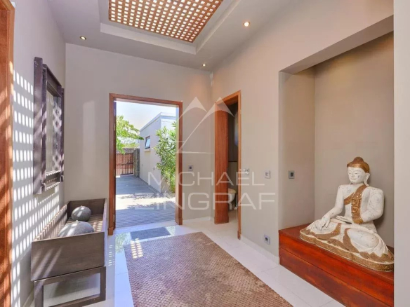 Intérieur d'une villa moderne avec un hall d'entrée lumineux et une statue de Bouddha.
