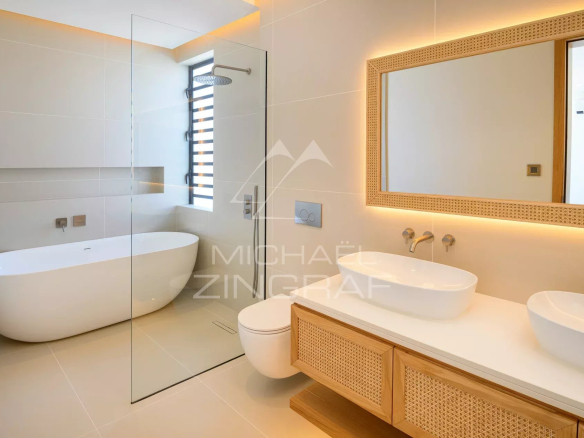 Salle de bain moderne avec baignoire, douche et double vasque dans une villa neuve.