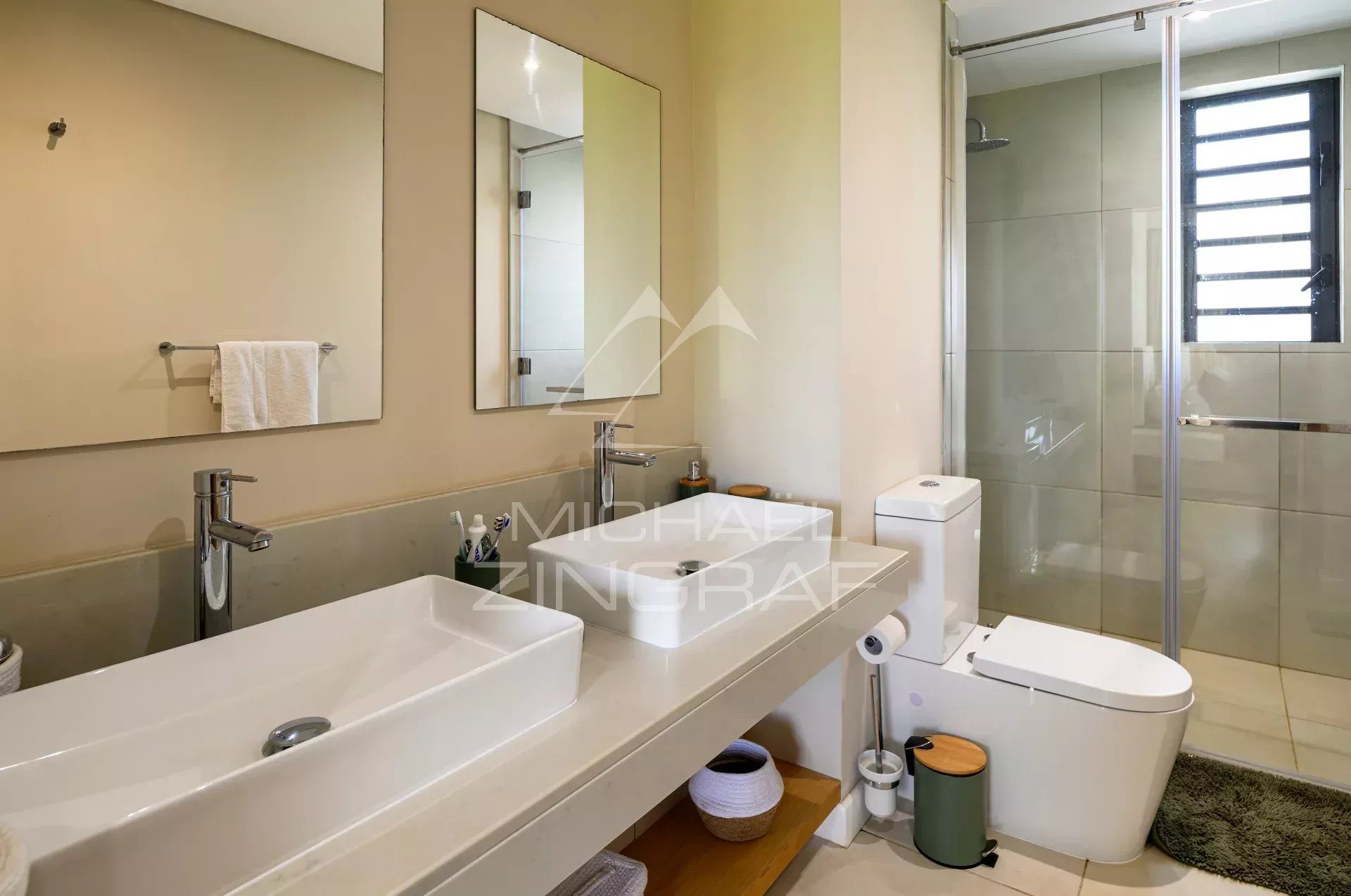 Salle de bain d’une villa à Azuri Salle de bain moderne avec lavabo, miroir et douche dans une villa à Azuri, Haute Rive.