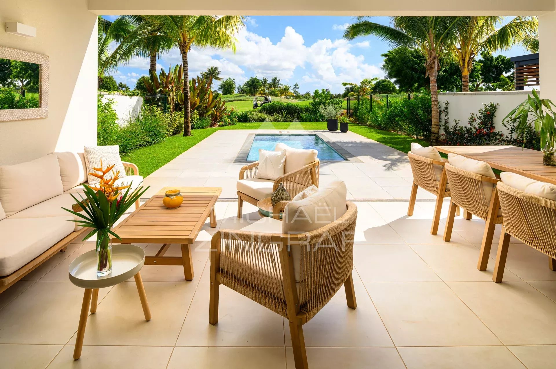 Villa jumelée à Azuri Terrasse d'une villa jumelée à Azuri avec salon extérieur et piscine, vue sur le jardin et le golf.