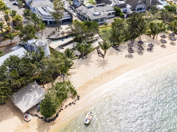 Vue aérienne d'une plage avec des parasols et des bâtiments en bord de mer.