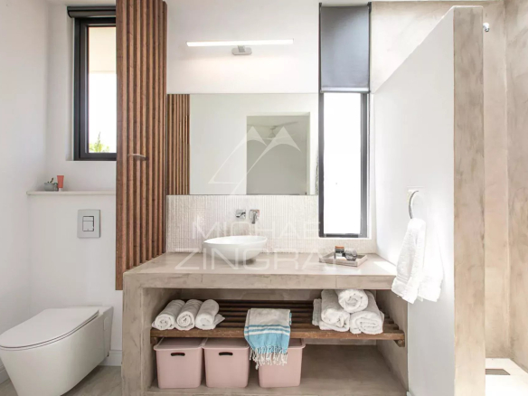 Salle de bain moderne avec lavabo, étagères et toilettes, dans une villa de luxe.