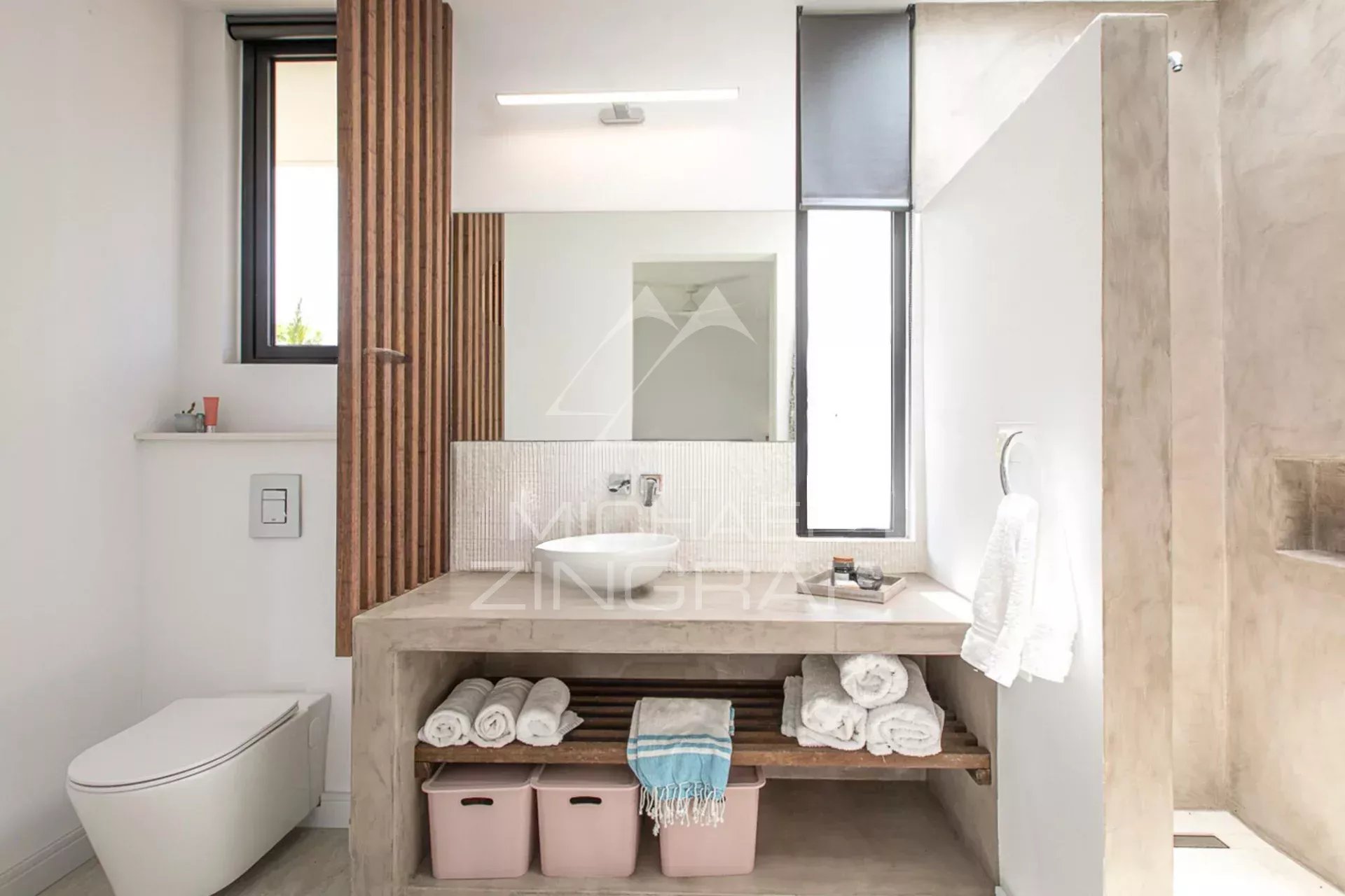 Salle de bain moderne avec lavabo, étagères et toilettes, dans une villa de luxe.