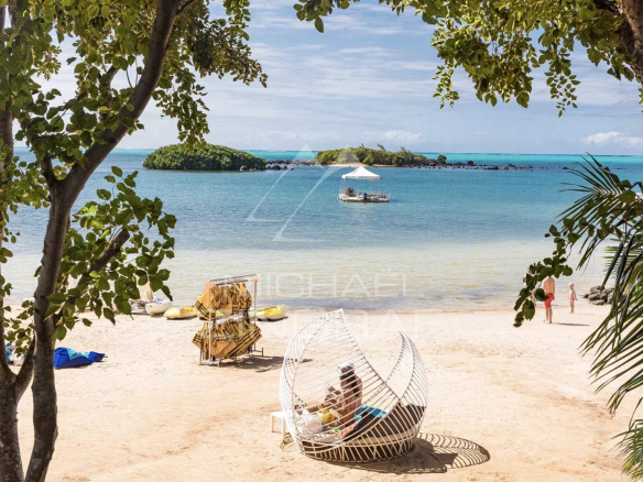 Plage avec vue sur l'eau et îlots, chaises longues et un bateau au loin.
