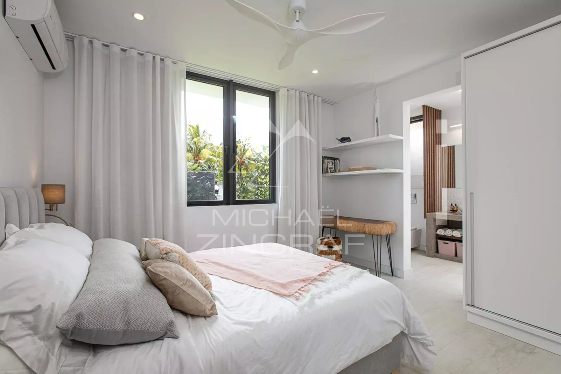 Chambre d'une villa de luxe avec lit, fenêtres et décoration moderne.