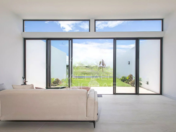 Intérieur d'une villa de luxe avec vue sur le golf, grandes fenêtres et mobilier moderne.