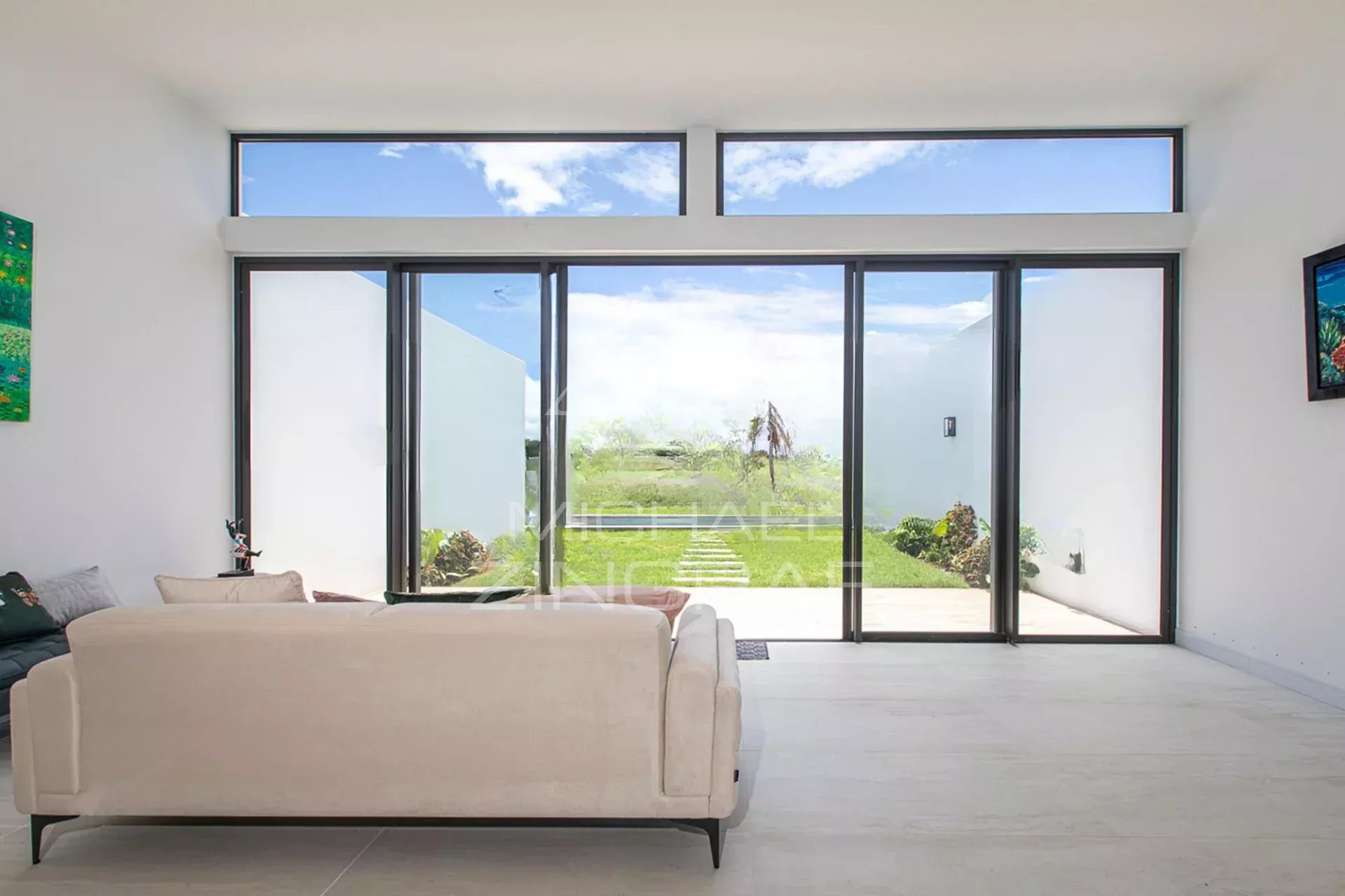 Intérieur d'une villa de luxe avec vue sur le golf, grandes fenêtres et mobilier moderne.
