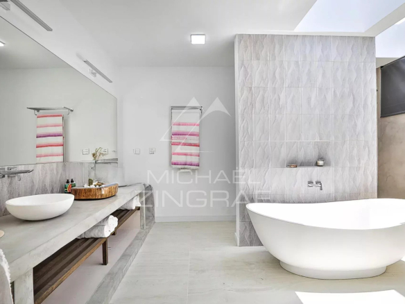 Salle de bain moderne avec baignoire et miroir, décorée de carrelage clair.