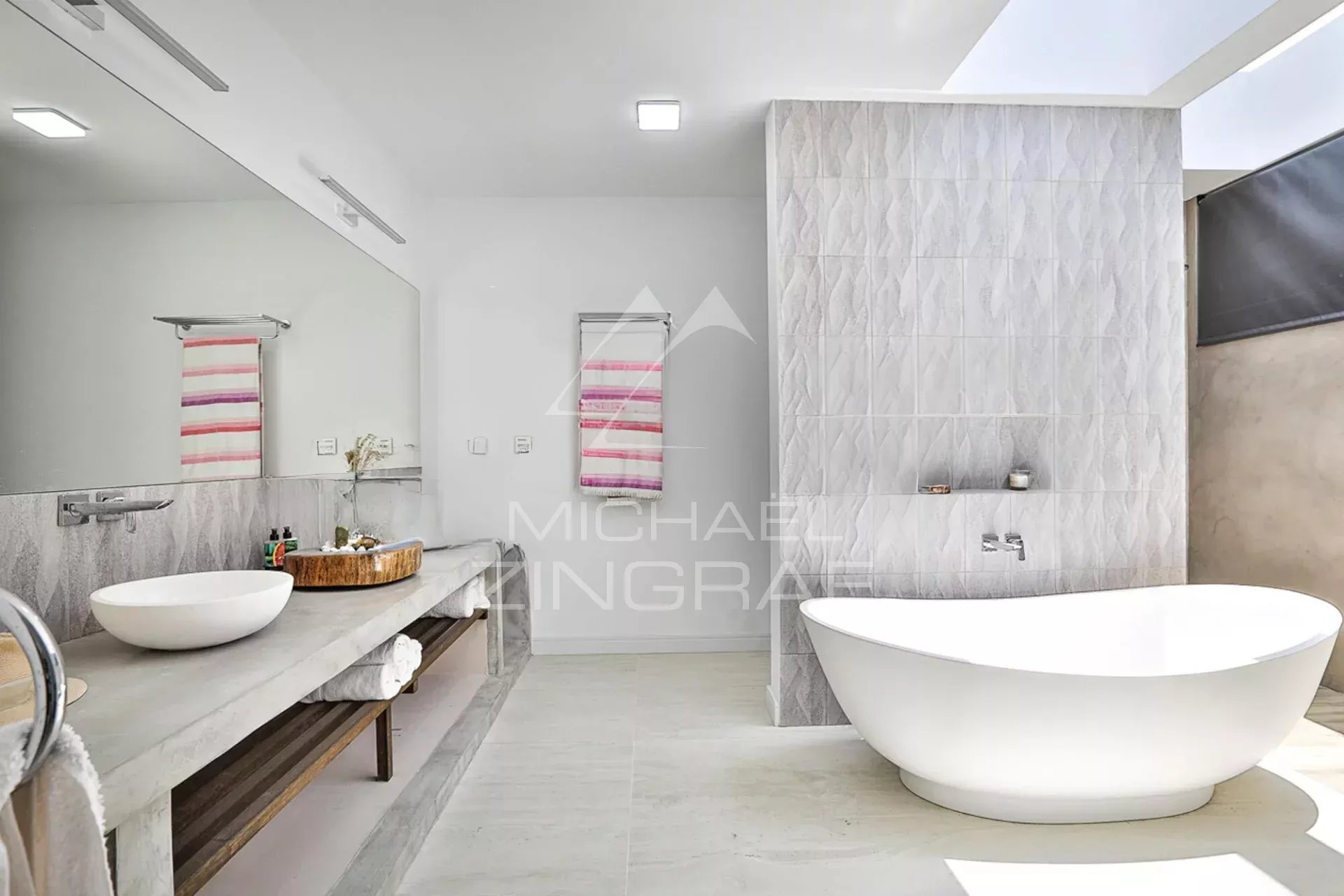 Salle de bain moderne avec baignoire et miroir, décorée de carrelage clair.