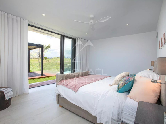 Chambre d'une villa de luxe avec vue sur le golf, décor moderne et lumineux.