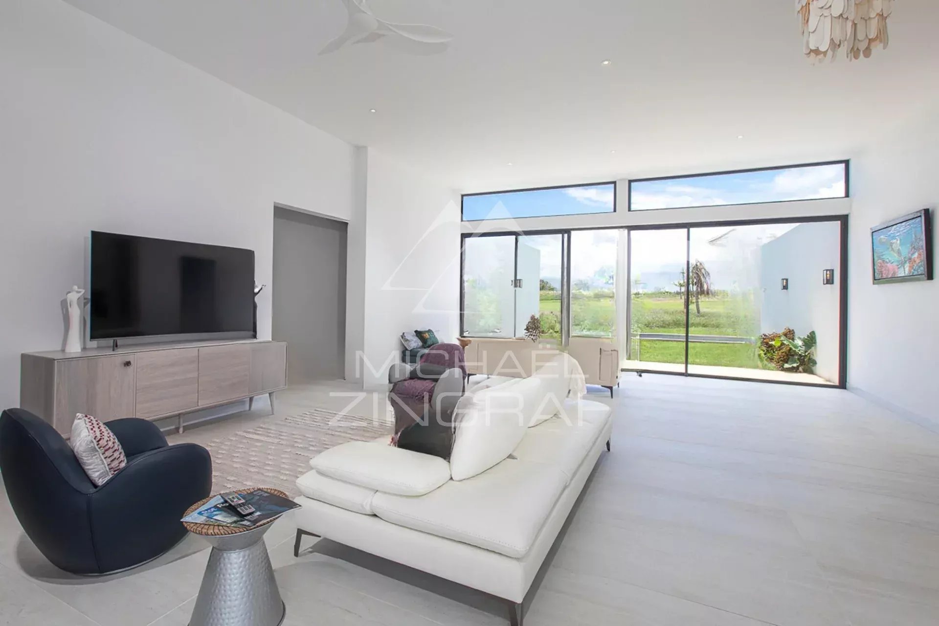 Intérieur d'une villa de luxe avec un salon moderne et lumineux, vue sur le jardin.