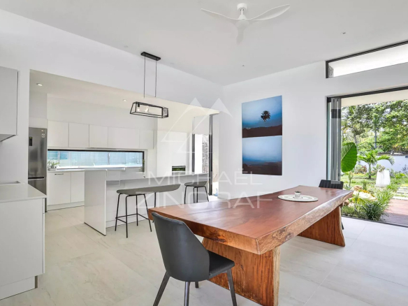 Intérieur moderne d'une villa de luxe avec une table en bois et une cuisine ouverte.