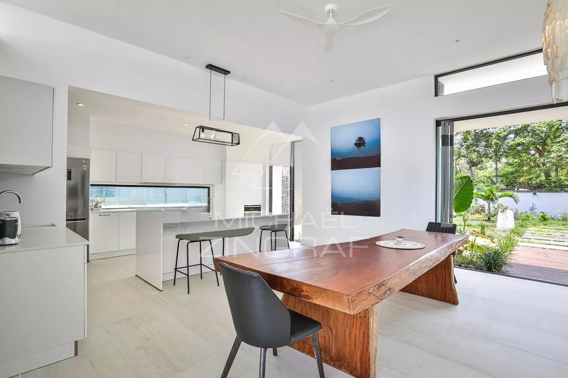 Intérieur moderne d'une villa de luxe avec une table en bois et une cuisine ouverte.