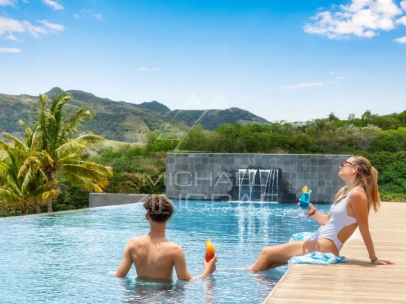 Two people relax by an infinity pool overlooking the mountains.