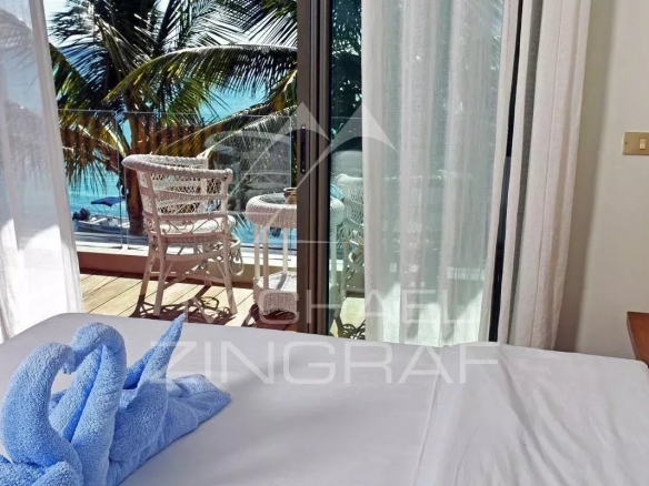 Room in an apartment with sea view in Pereybere, bed and balcony with chairs.