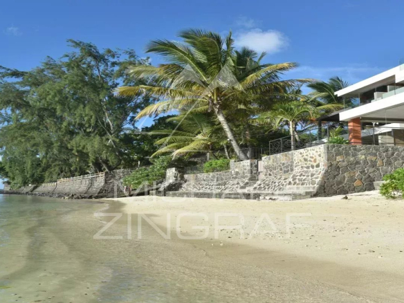 Beach with a seaside apartment in Pereybere, surrounded by palm trees and calm water.