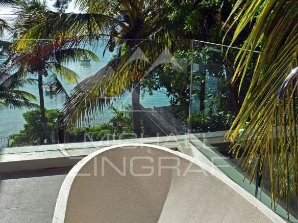 Terrace of an apartment with sea view in Pereybere, surrounded by palm trees.
