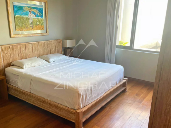 Chambre d'un appartement élégant avec lit double et fenêtre lumineuse.