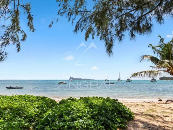 Plage de Bain Bœuf avec vue sur la mer et des bateaux au loin.