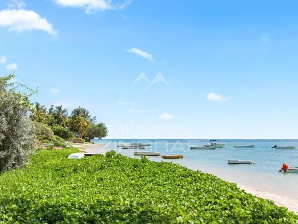 Plage de Bain Bœuf avec des bateaux et de la végétation en bord de mer.