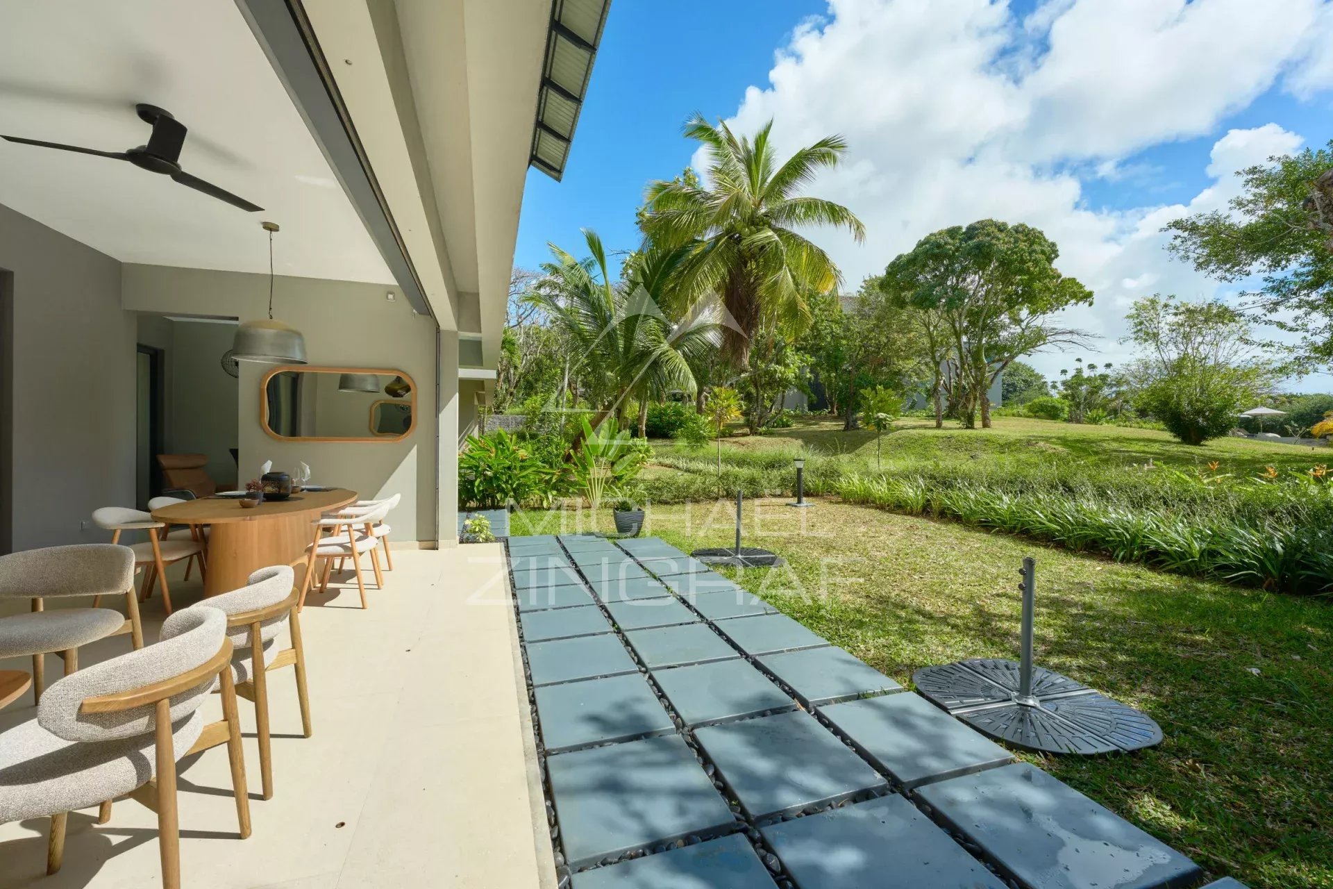Apartment terrace with private garden in Belle Vue, surrounded by greenery and palm trees.