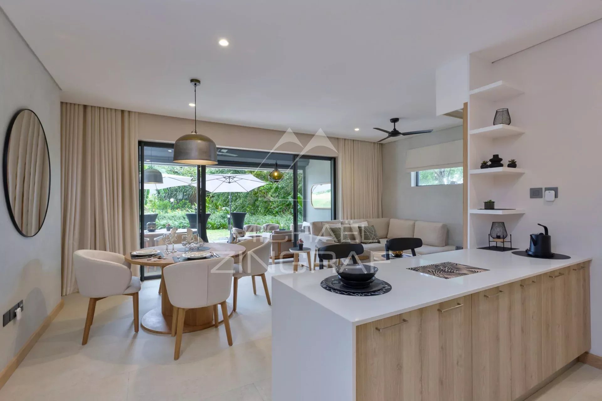 Interior of a modern apartment with living room, dining room and open kitchen, overlooking a garden.