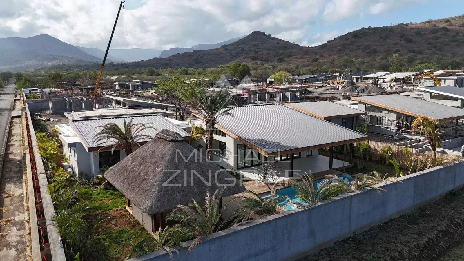 Villa contemporaine à Tamarin Vue aérienne d'une villa contemporaine en construction à Tamarin, entourée de nature et de montagnes.