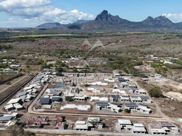 Vue aérienne du projet immobilier Eko Savannah à Tamarin, montrant des villas en construction et un paysage montagneux.