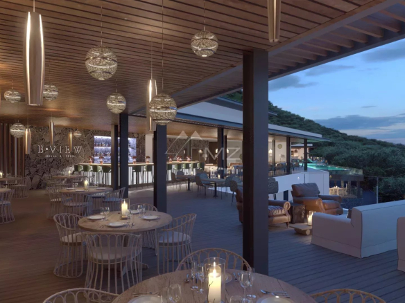 Terrasse d'une villa avec tables, chaises et éclairage décoratif, vue sur la piscine et la nature environnante.