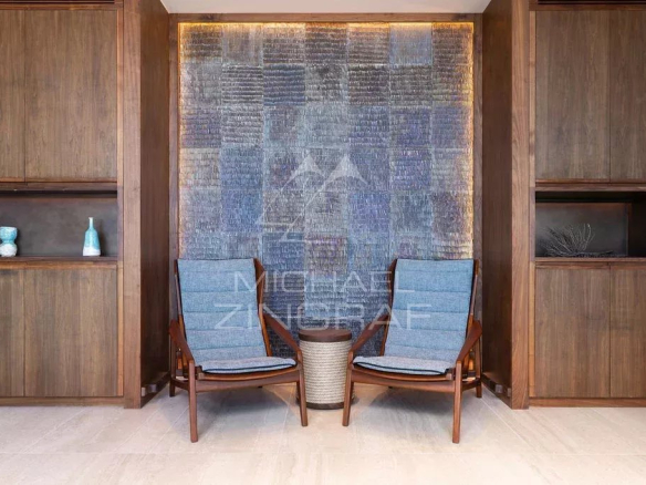 Intérieur d'un penthouse avec deux chaises en bois et un mur décoratif en verre.