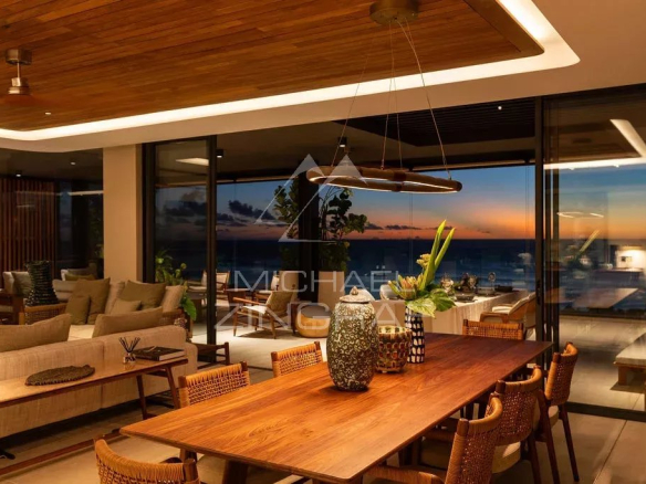 Intérieur d'un penthouse avec vue sur l'océan, mobilier moderne et éclairage chaleureux.