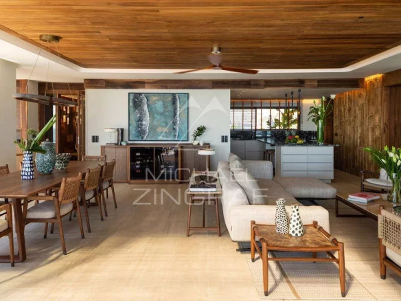Intérieur d'un penthouse moderne avec mobilier en bois et grandes fenêtres donnant sur l'océan.