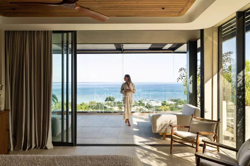 Penthouse avec vue sur l’océan Intérieur d'un penthouse avec vue sur l'océan Indien à Rivière Noire, femme en peignoir sur le balcon.