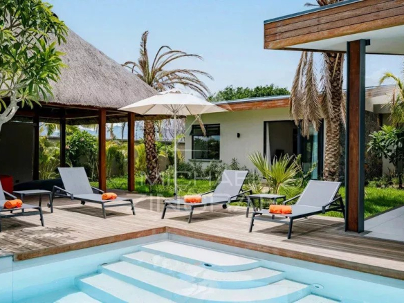Terrasse de la Villa Hibiscus à Tamarin avec piscine à débordement et chaises longues.