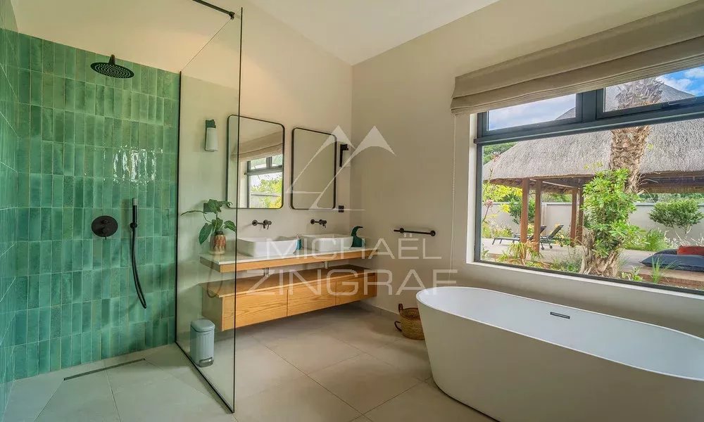 Salle de bain contemporaine de la Villa Hibiscus Salle de bain moderne avec douche à l'italienne et baignoire, ouverte sur un jardin.