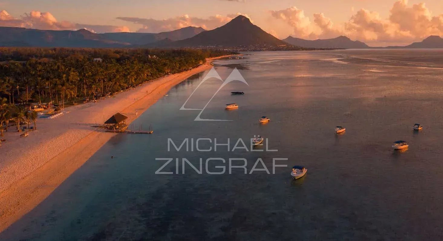 Plage de Tamarin au coucher de soleil Vue aérienne de la plage et des bateaux à Tamarin, avec des montagnes en arrière-plan au coucher de soleil.