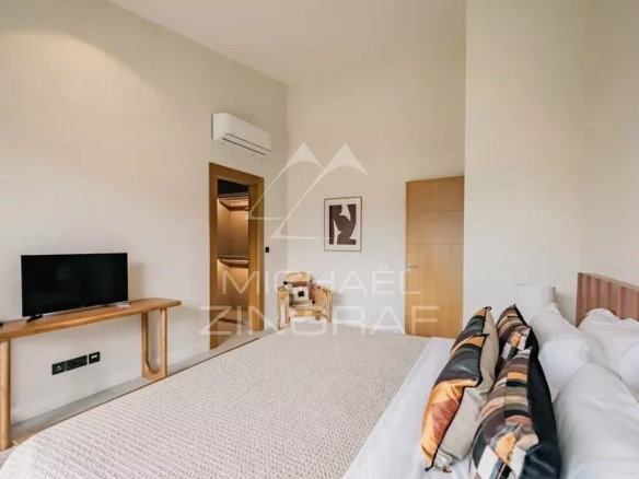 Chambre d'une villa contemporaine avec télévision et lit, décorée de manière élégante.
