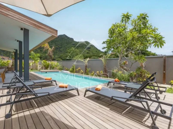 Terrasse avec chaises longues et piscine à débordement dans une villa contemporaine à Tamarin.