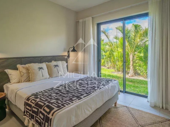 Chambre moderne avec lit double et vue sur le jardin tropical à Tamarin.