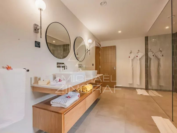 Salle de bain moderne avec deux lavabos, miroir rond et douche en verre
