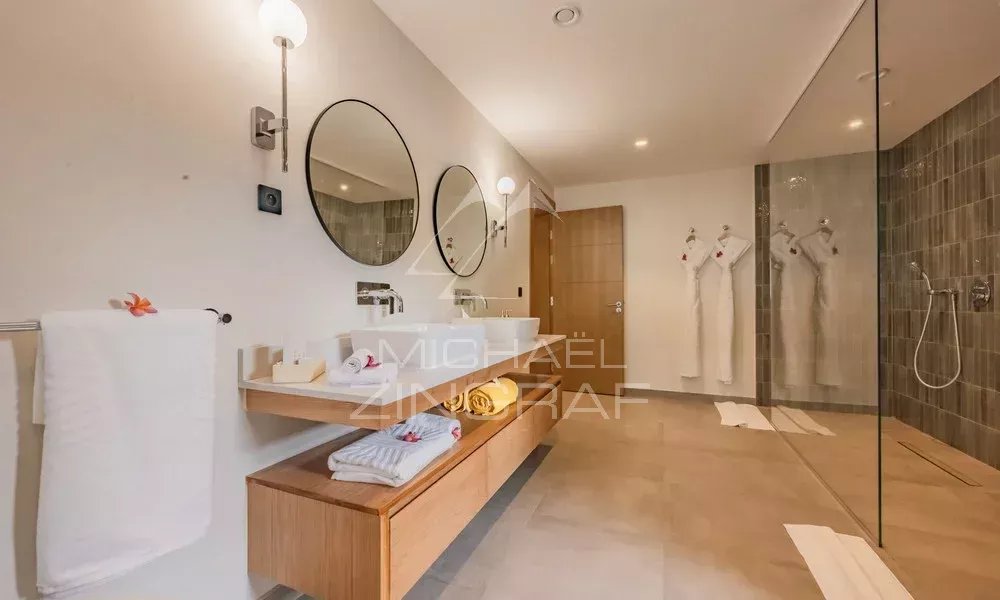 Salle de bain d’un appartement avec vue sur l’océan Salle de bain moderne avec deux lavabos, miroir rond et douche en verre