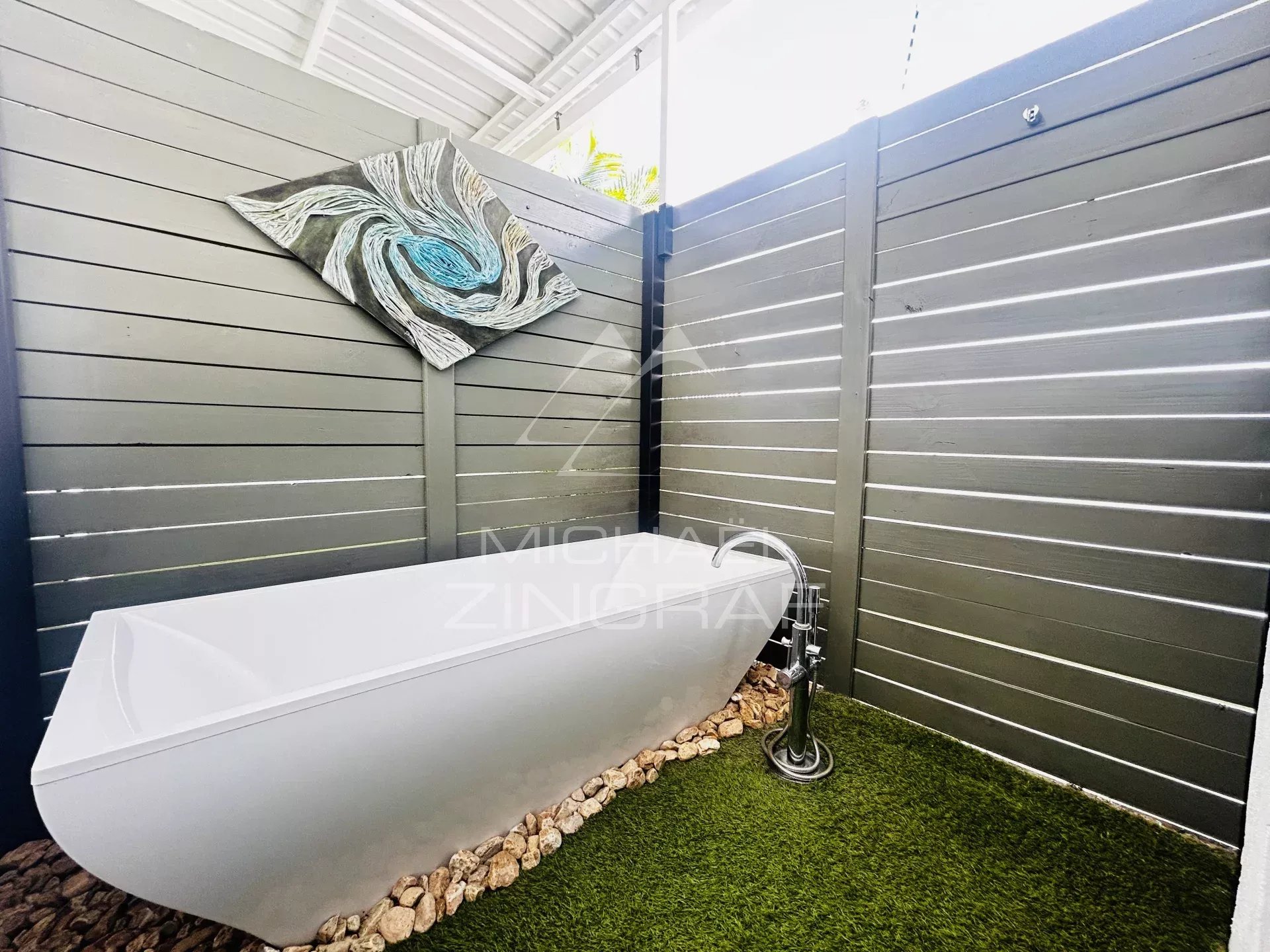 Outdoor bathtub in Pereybère Modern outdoor bathtub in a private space with wooden walls and wall decorations.