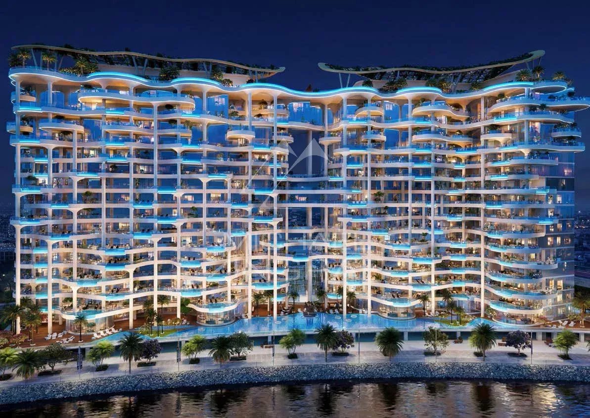 Immeuble résidentiel contemporain à Dubaï, éclairé la nuit avec piscine et jardins.