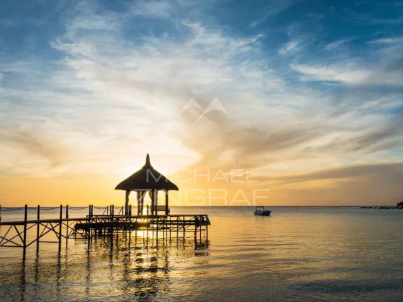 Sunset on a wooden pontoon with a shelter by the water in Tamarin.